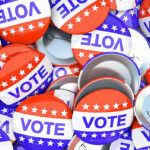 Red, white, and blue "VOTE" buttons with stars scattered in a pile.