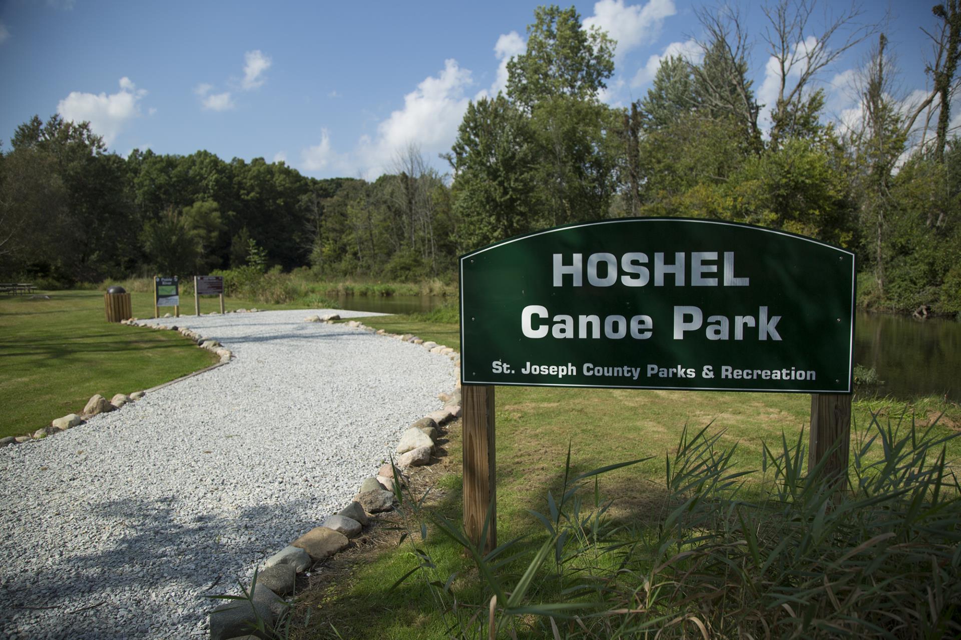 Hoshel Canoe Park entrance sign with gravel path and St. Joseph County Parks & Recreation information visible.